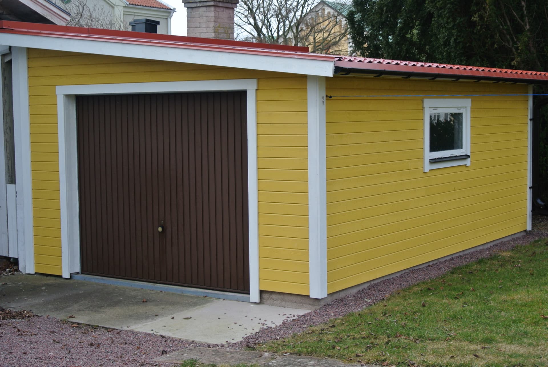 Gult garage med brun port — Tillbyggnad